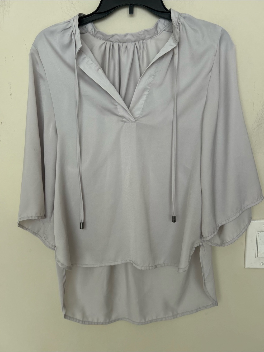 light grey V-neck blouse featuring delicate drawstring neck ties high-low hem.